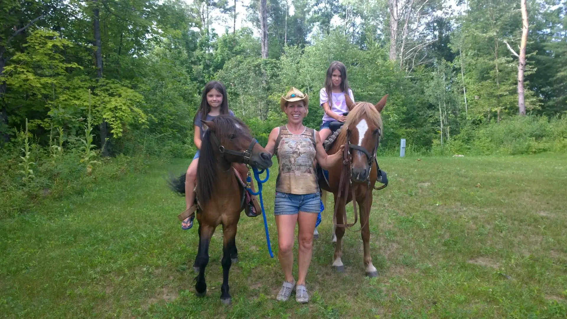 Women leading 2 girls on horses