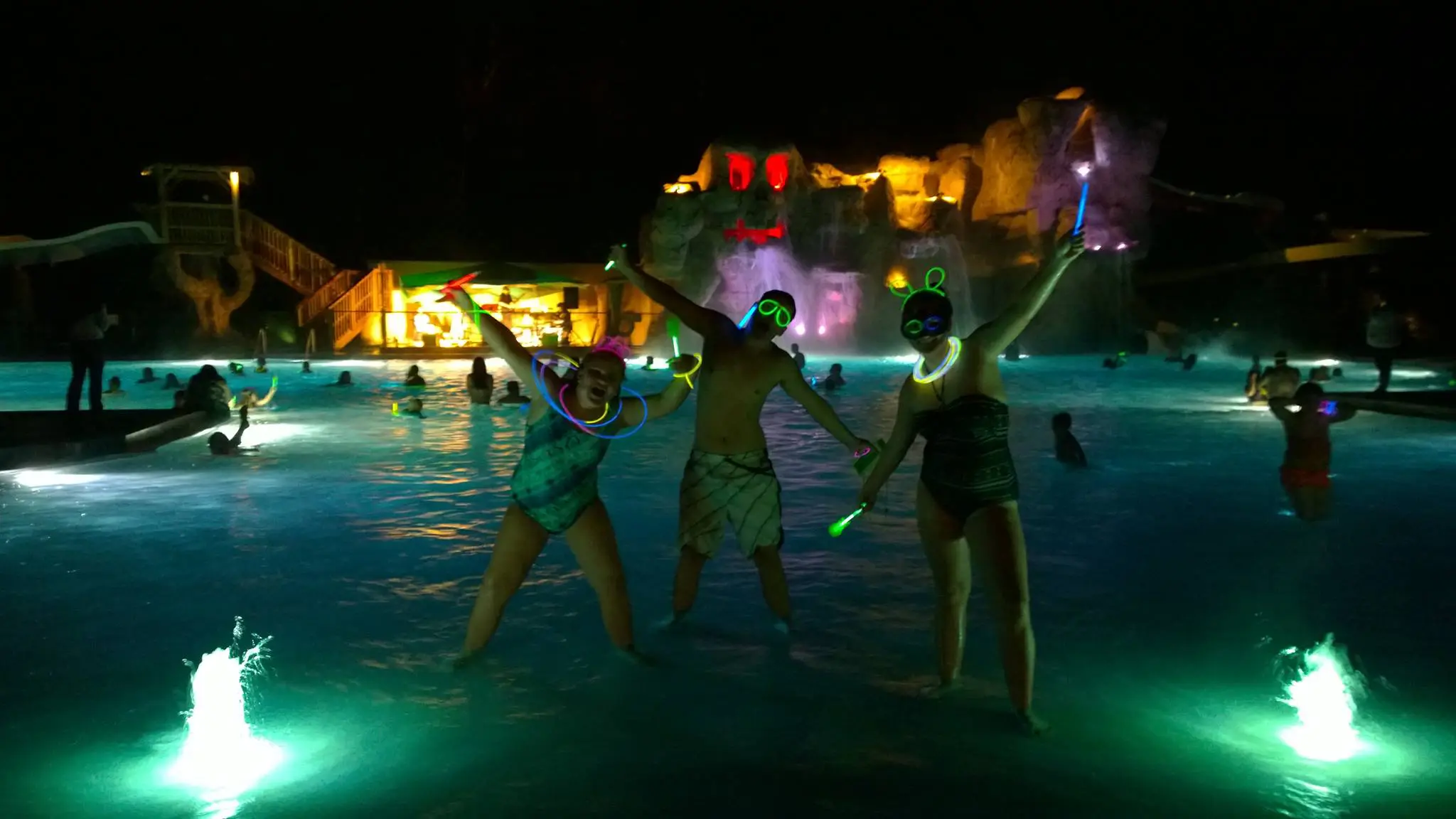 Kids in pool with glow sticks at night
